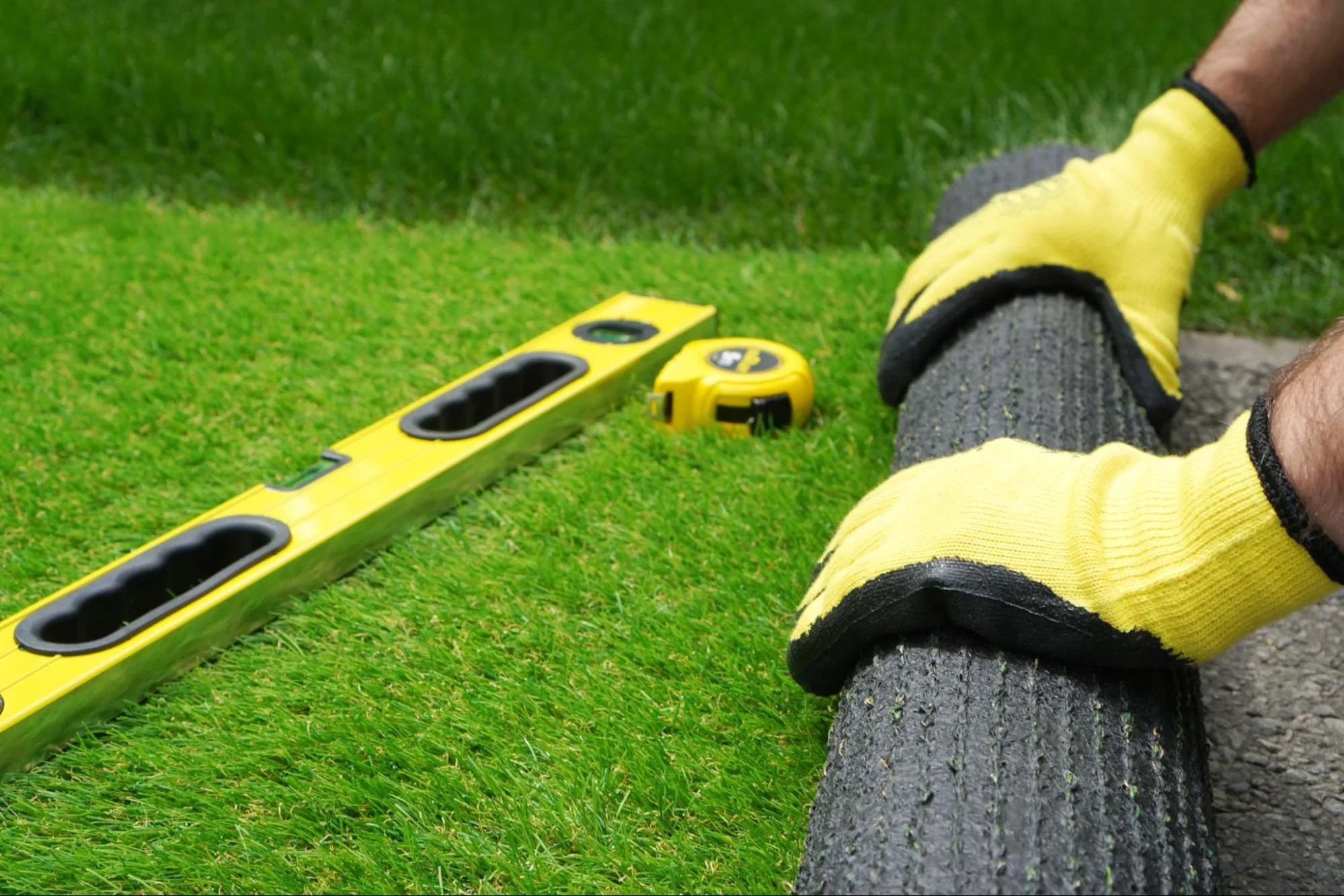 big-bully-turf-installing-fake-grass-roll-measuring-tape-level