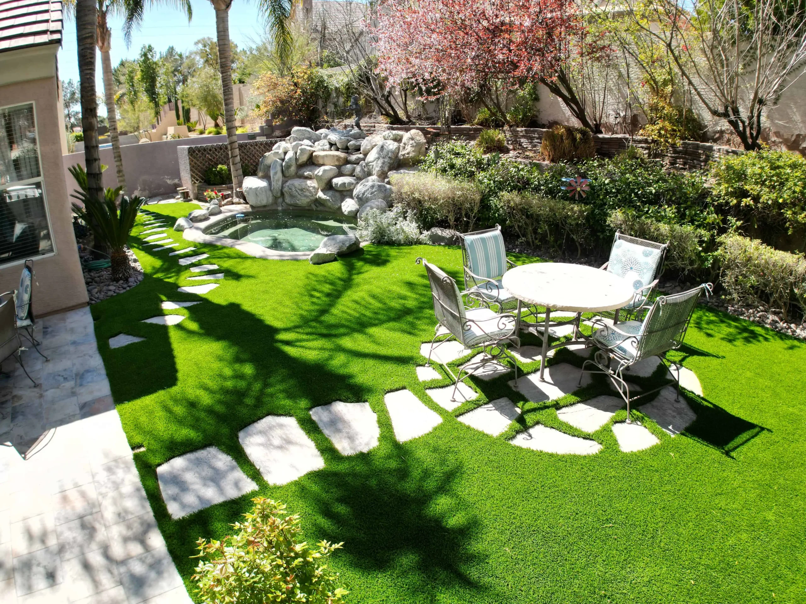 Grass installation with stone walkway in back yard installed by big bully turf
